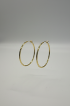 Gold hoop earrings on a gray background