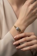 Close-up of a hand wearing a bracelet with a polka dot charm on a neutral background
