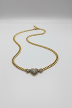 Gold chain necklace with a heart-shaped pendant on a light gray background