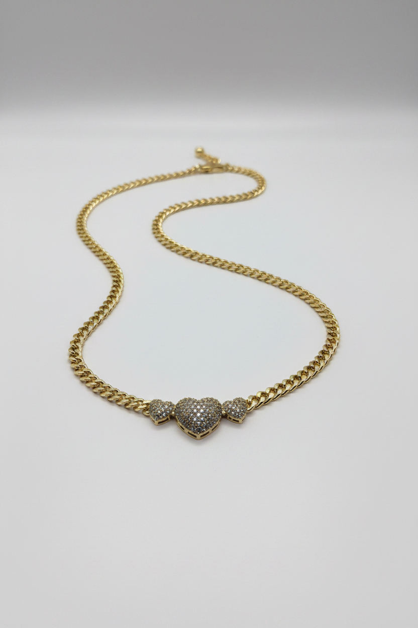 Gold chain necklace with a heart-shaped pendant on a light gray background
