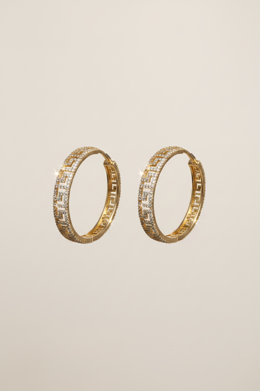 Pair of gold hoop earrings with embedded stones on a beige background