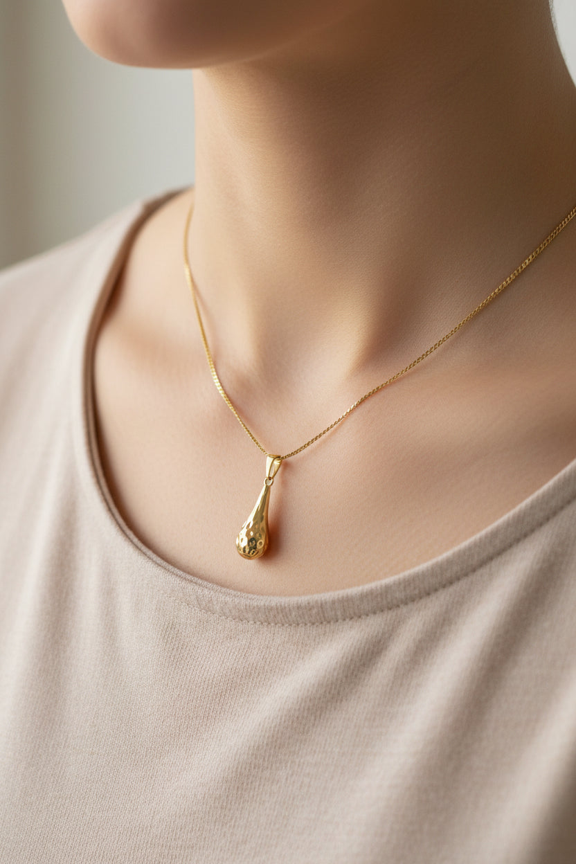 Gold necklace with a pendant on a neutral background