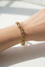 Gold bracelet on a wrist with a light background