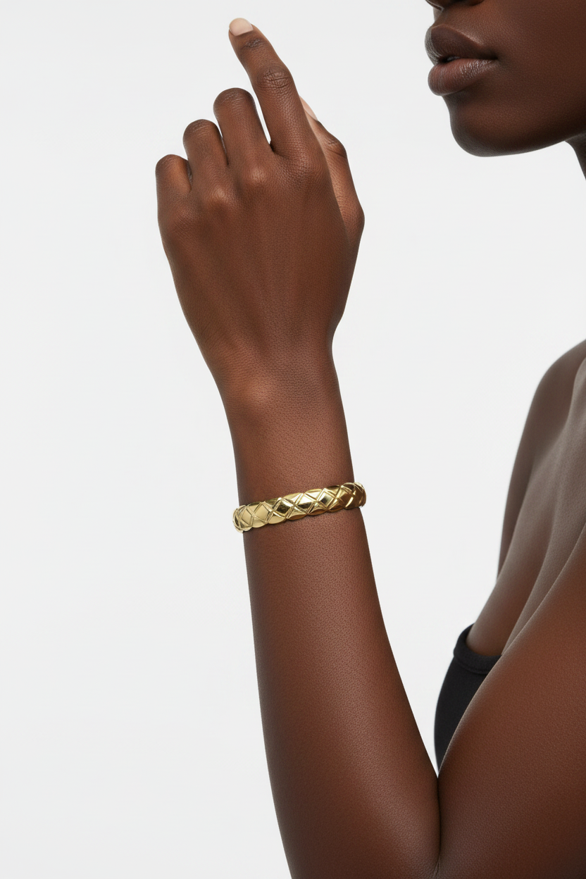 Gold bracelet on a wrist with a neutral background