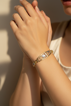 Close-up of a hand wearing a gold bracelet with intricate designs.