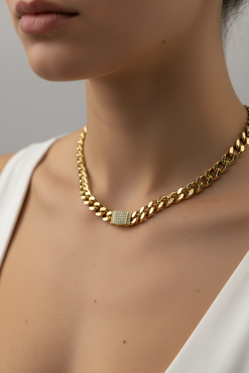 Gold chain necklace worn by a person against a neutral background