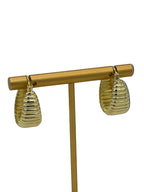 Gold earrings with ribbed design on a light gray background